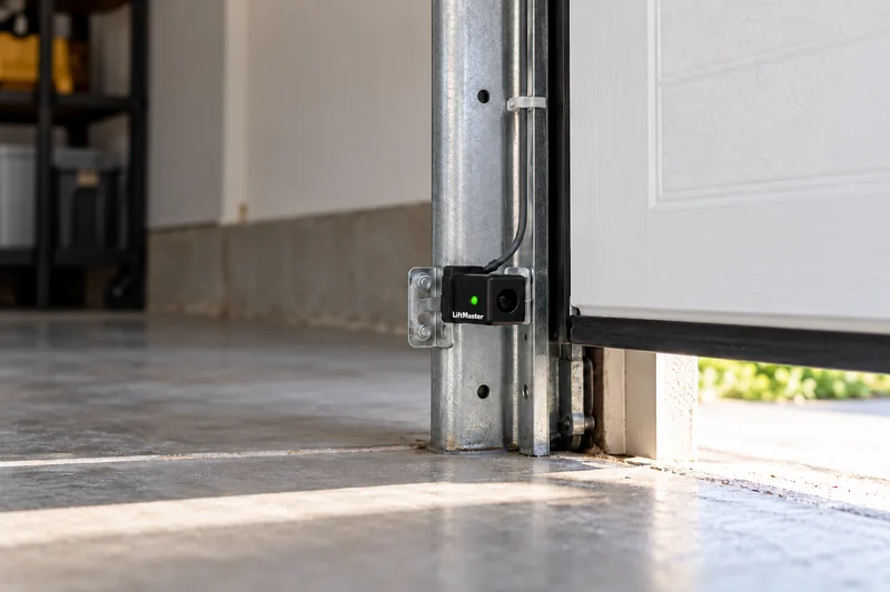 Illustrative photoelectric safety sensor mounted near the bottom of a garage door track